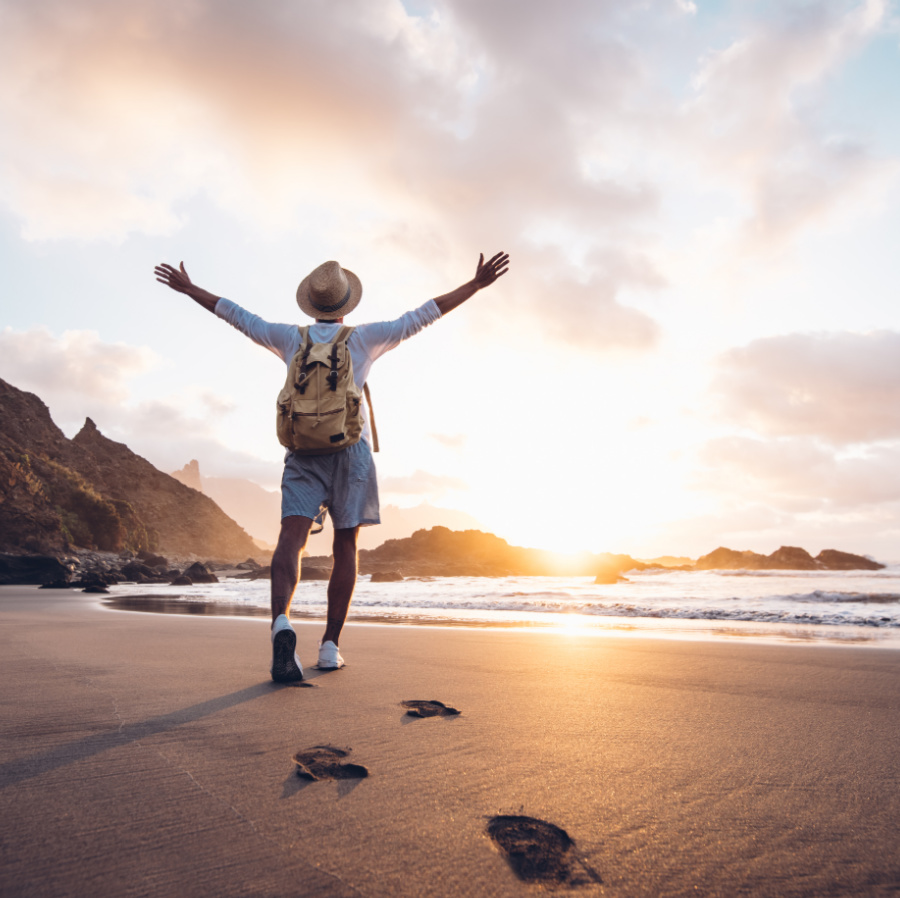 Man celebrating overcoming travel fears on the beach with arms up